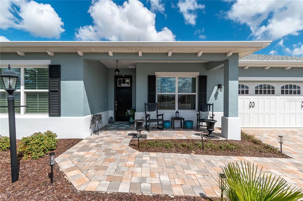 The exterior of a house features a paver walkway, a covered porch, and a garage — 10307 SW 96TH LANE, OCALA, FL
