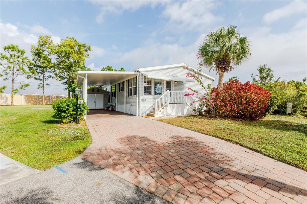 A single-story manufactured home features a paved driveway, a carport, and a small front porch — 2100 KINGS HIGHWAY UNIT 376, PORT CHARLOTTE, FL