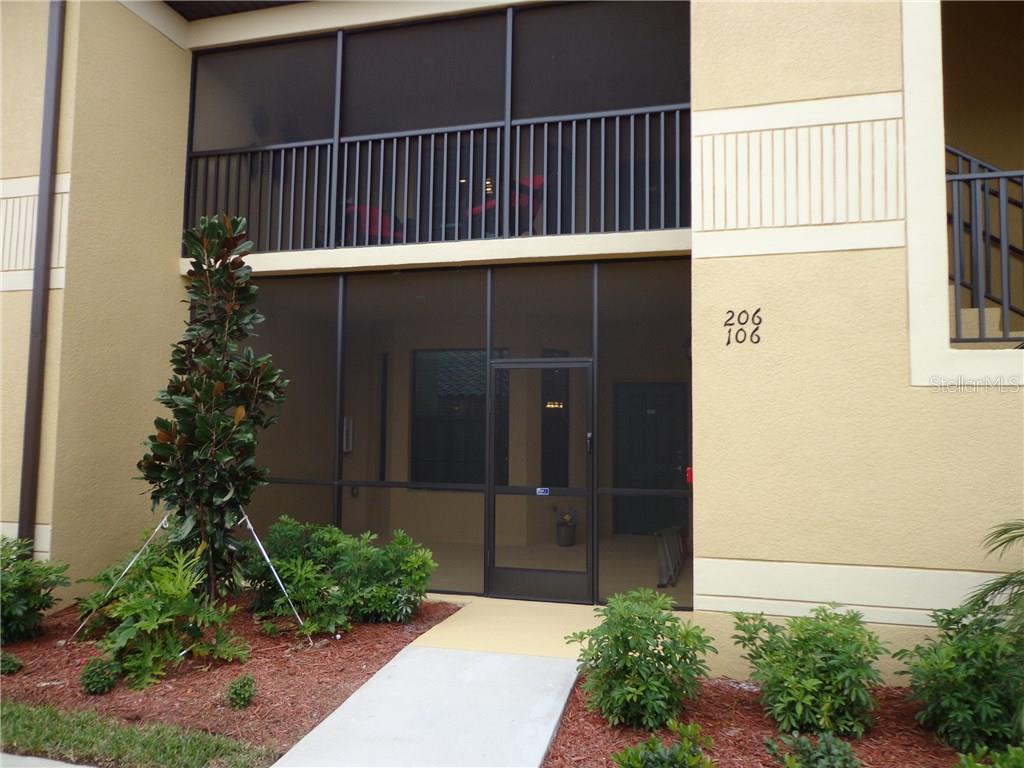 A two-story building exterior features a screened-in ground floor patio and an upper balcony — 6715 GRAND ESTUARY TRAIL UNIT 106, BRADENTON, FL