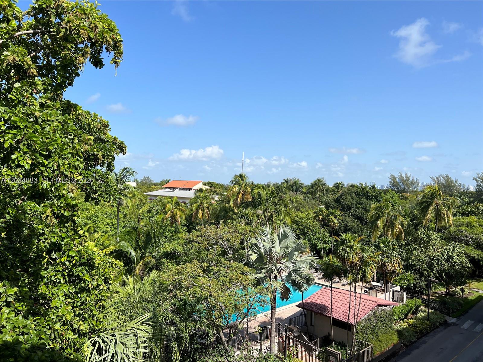 An elevated view shows a swimming pool surrounded by lush tropical trees and buildings — 101 Crandon Blvd # 474, Key Biscayne FL 33149, KEY BISCAYNE, FL