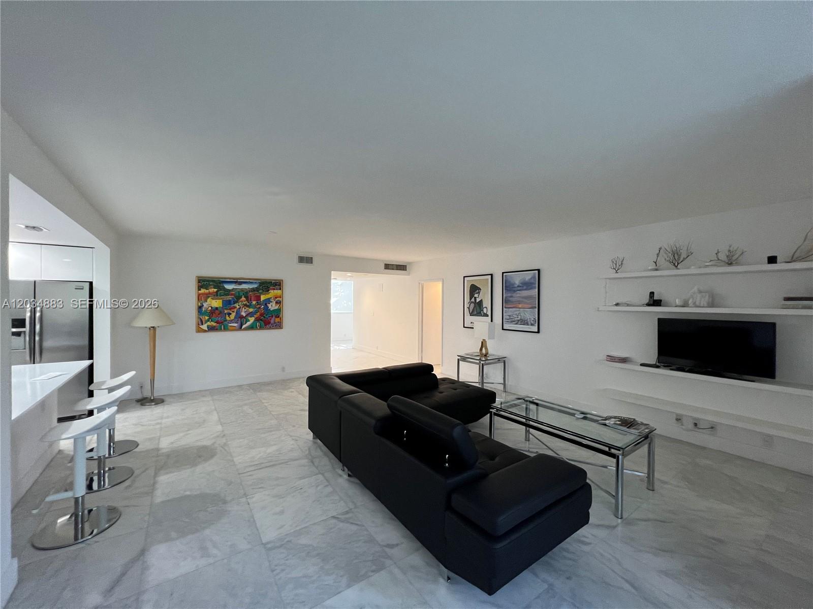 A modern living room features white marble floors, a black leather sofa, and white shelving — 101 Crandon Blvd # 474, Key Biscayne FL 33149, KEY BISCAYNE, FL