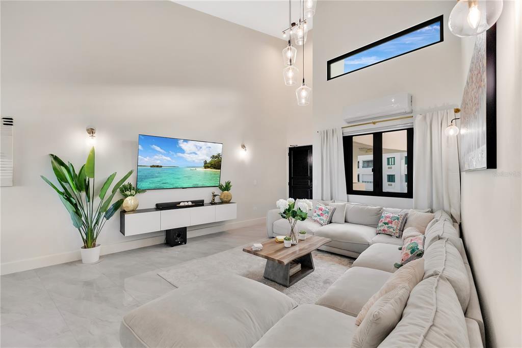 A modern living room features a large sectional sofa, wall-mounted television, and high vaulted ceilings — 6000 RIO MAR BOULEVARD UNIT 7131, RIO GRANDE, PR