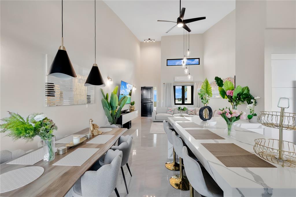 A modern open-concept dining and kitchen area features high ceilings, tile flooring, and pendant lighting — 6000 RIO MAR BOULEVARD UNIT 7131, RIO GRANDE, PR