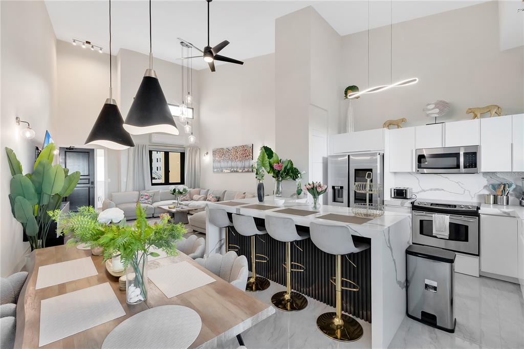 An open-concept kitchen and dining area features a marble island, bar stools, and high ceilings — 6000 RIO MAR BOULEVARD UNIT 7131, RIO GRANDE, PR