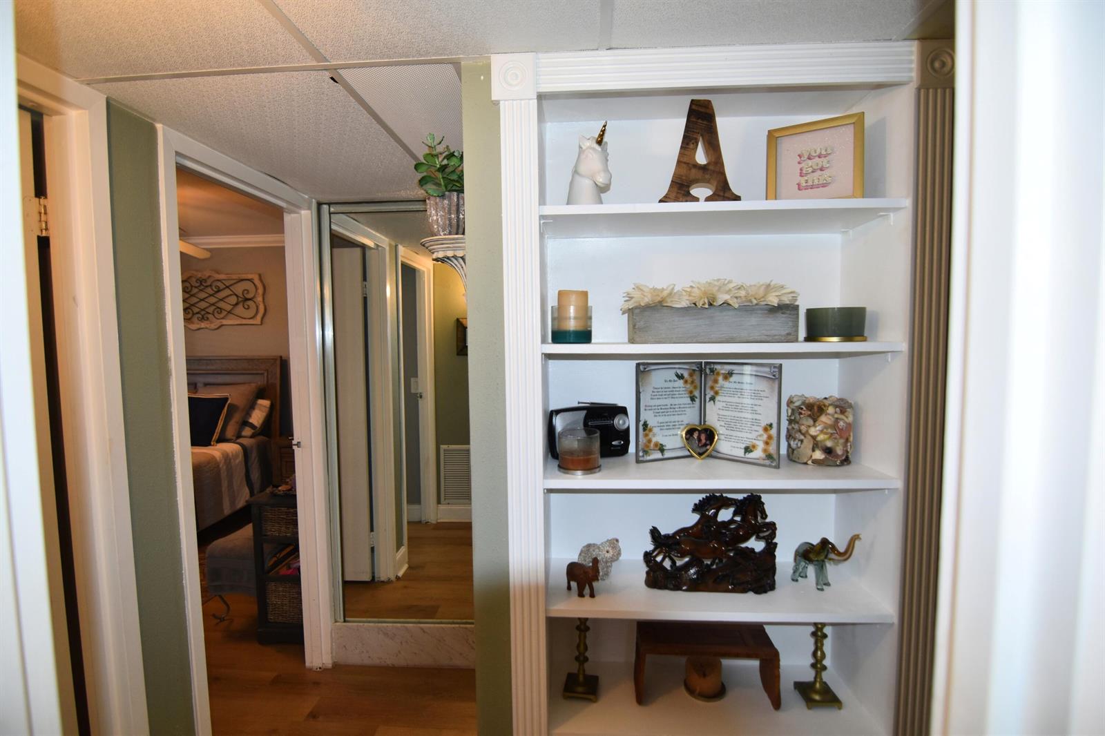 A white built-in bookshelf stands next to a doorway leading into a bedroom — 237 Saxony E, Delray Beach FL 33446, DELRAY BEACH, FL