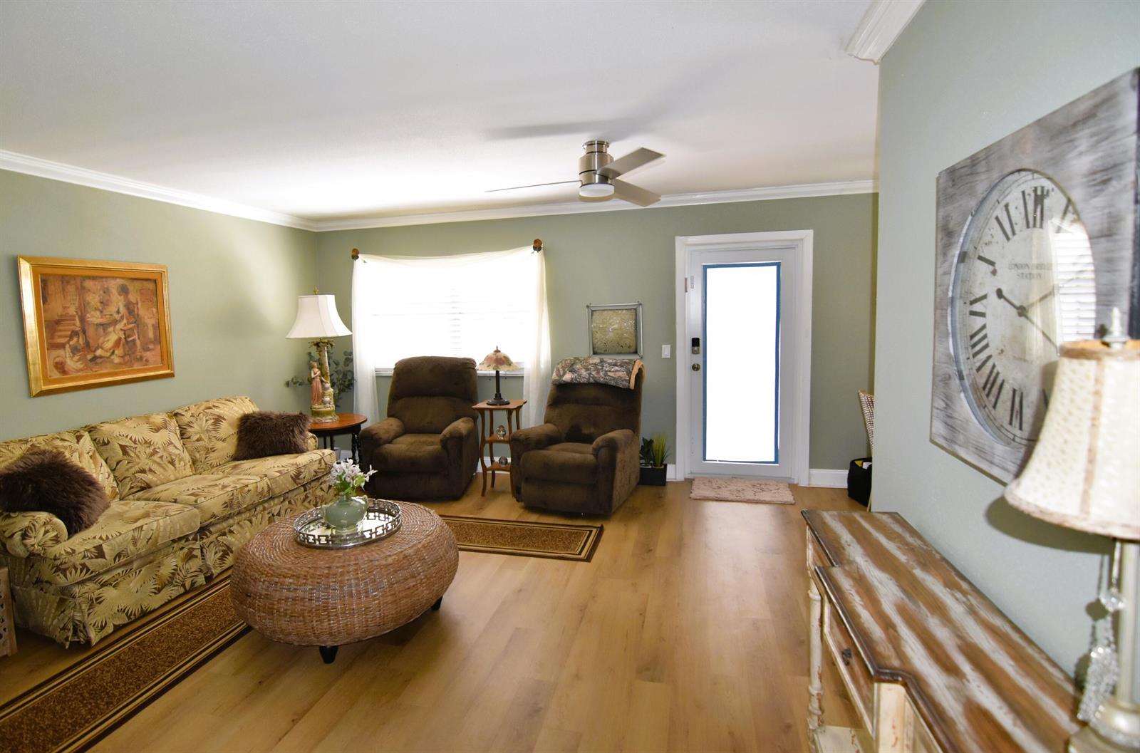 A living room with light green walls, wood flooring, a patterned sofa, and two recliners — 237 Saxony E, Delray Beach FL 33446, DELRAY BEACH, FL