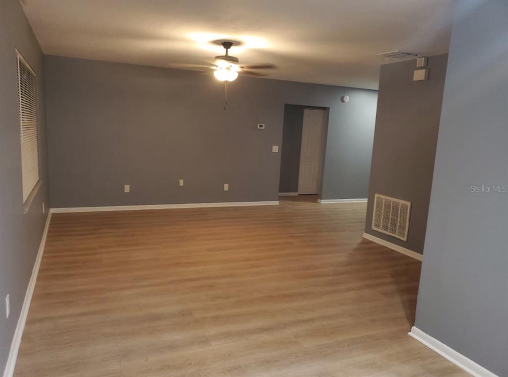 An empty room features gray walls, light wood-look flooring, and a ceiling fan — 8211 CLERMONT STREET, TAMPA, FL