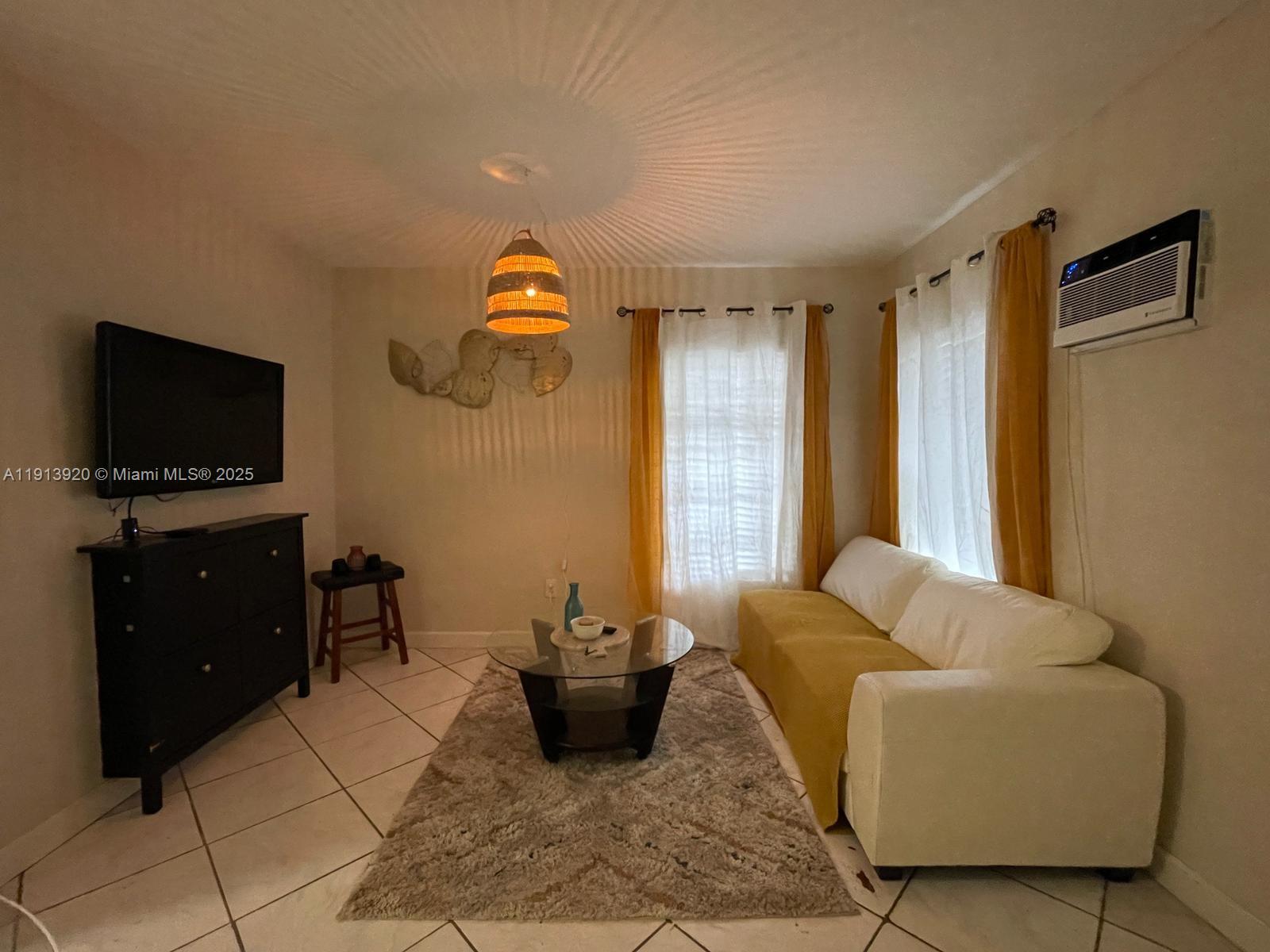 A living room features a white sofa, a glass coffee table, and a black dresser — 55 NW 69th St, Miami FL 33150, MIAMI, FL