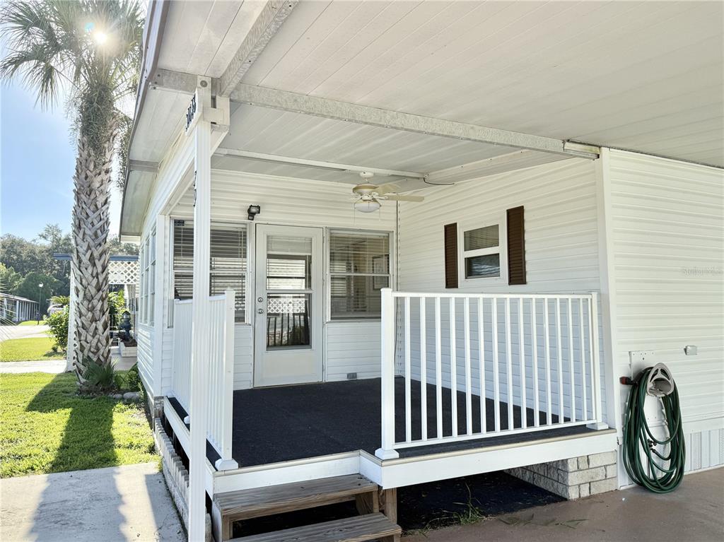 A white mobile home features a covered front porch with a railing and a ceiling fan — 34648 SWEETPEA LANE, ZEPHYRHILLS, FL