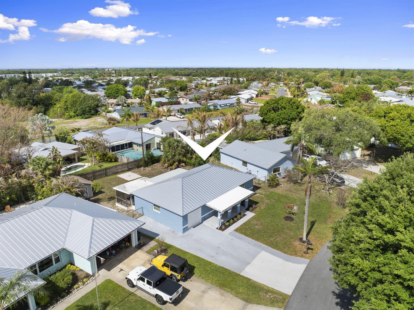 An aerial view shows a blue house with a metal roof and a concrete driveway — 2268 NE 16th Court, Jensen Beach FL 34957, JENSEN BEACH, FL