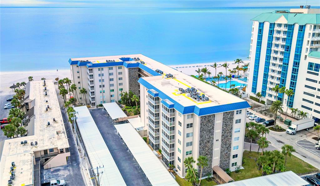 An aerial view shows a multi-story apartment complex with covered parking near a sandy beach — 800 BENJAMIN FRANKLIN DRIVE UNIT 406, SARASOTA, FL