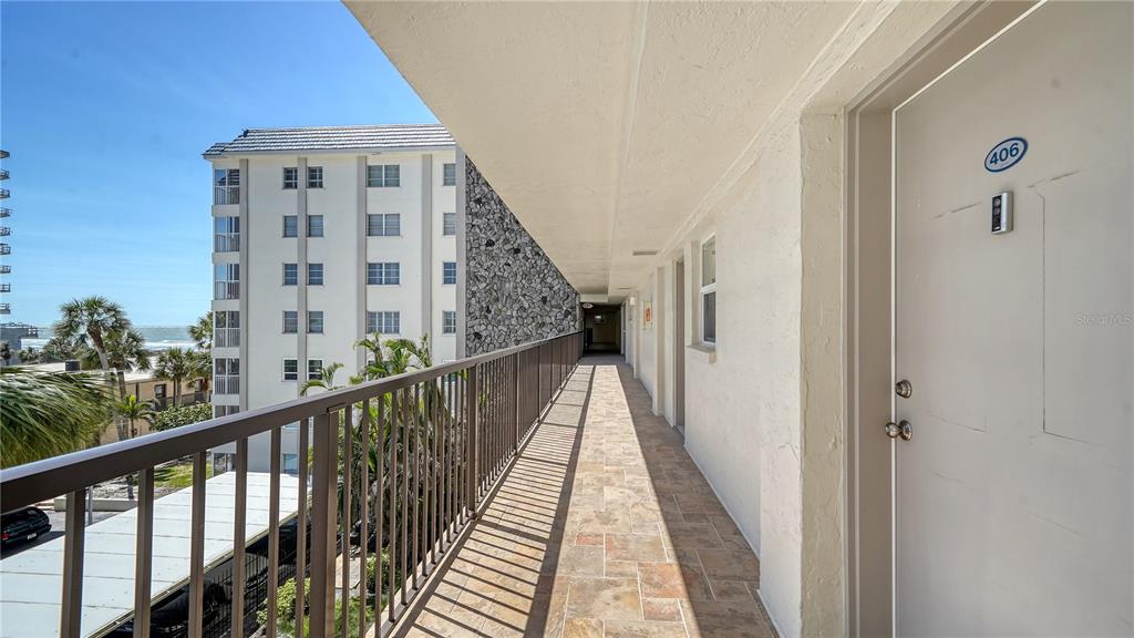 An outdoor walkway with tile flooring, a metal railing, and a door labeled 406 — 800 BENJAMIN FRANKLIN DRIVE UNIT 406, SARASOTA, FL