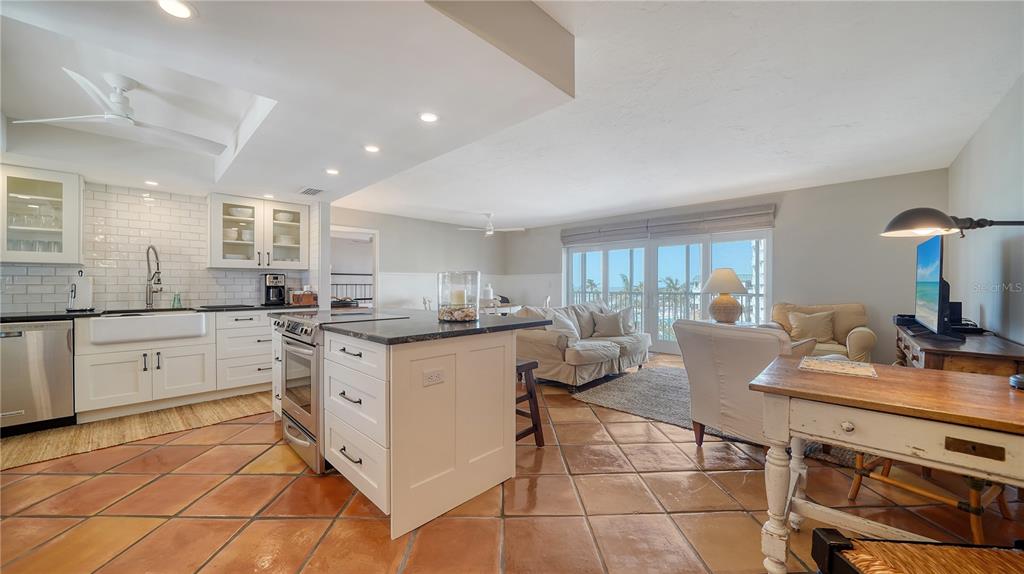 An open-concept kitchen and living area features terracotta tile flooring and a white kitchen island — 800 BENJAMIN FRANKLIN DRIVE UNIT 406, SARASOTA, FL