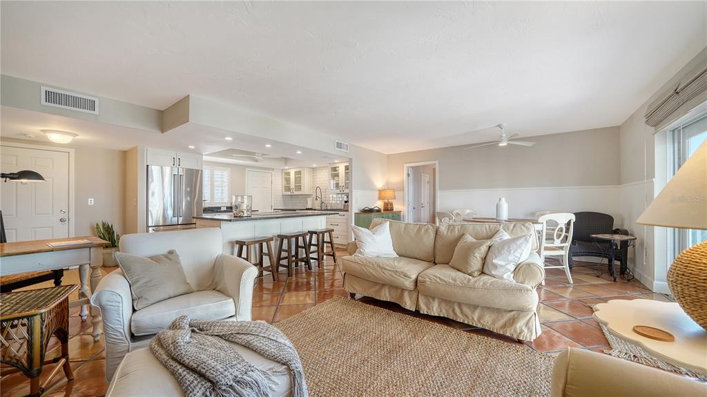 An open-concept living room and kitchen feature tile flooring, neutral furniture, and a kitchen island — 800 BENJAMIN FRANKLIN DRIVE UNIT 406, SARASOTA, FL