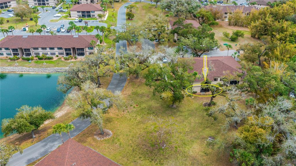 An aerial view shows a multi-story building with a screened-in patio near a lake — 19505 QUESADA AVENUE UNIT H101, PORT CHARLOTTE, FL