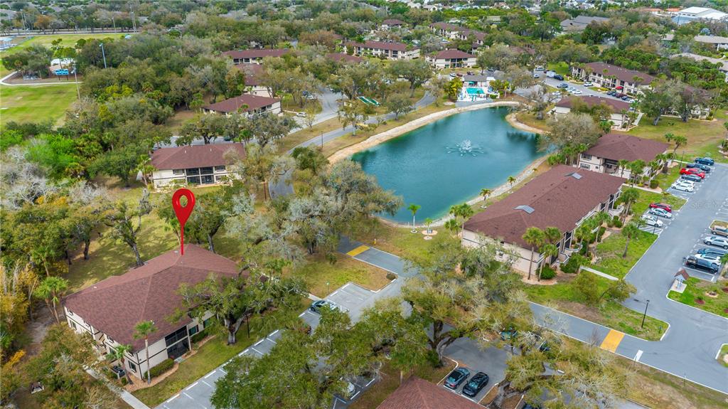 An aerial view shows a multi-story apartment building with a red pin, a pond, and parking — 19505 QUESADA AVENUE UNIT H101, PORT CHARLOTTE, FL
