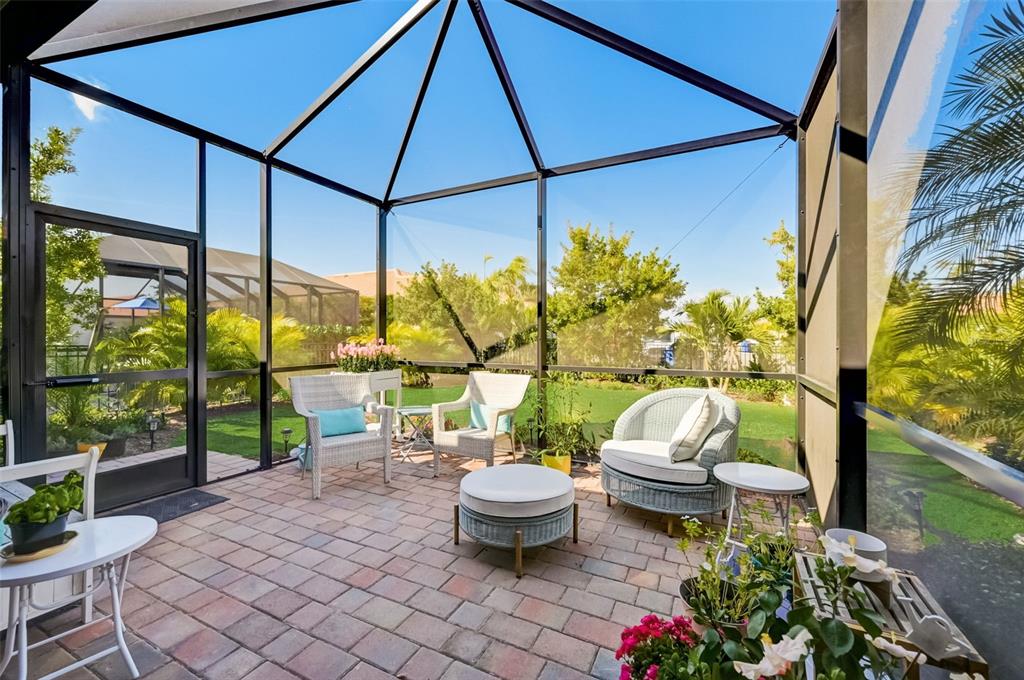 A screened-in patio with brick pavers, wicker furniture, and a view of a grassy yard — 113 VINADIO BOULEVARD, NOKOMIS, FL