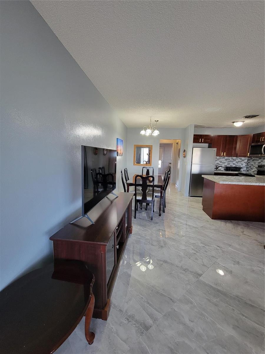 A living area with a television console leads into a dining space and open kitchen — 800 SW 11th Avenue # 17, Hallandale Beach FL 33009, HALLANDALE BEACH, FL