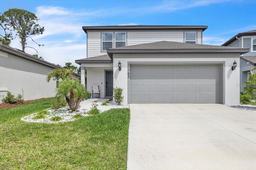 A two-story house features a gray garage, white siding, and a small front yard — 11783 MOONSAIL DRIVE, PARRISH, FL