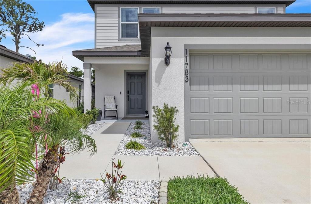 The exterior of a two-story house features a gray garage door and a front entryway — 11783 MOONSAIL DRIVE, PARRISH, FL