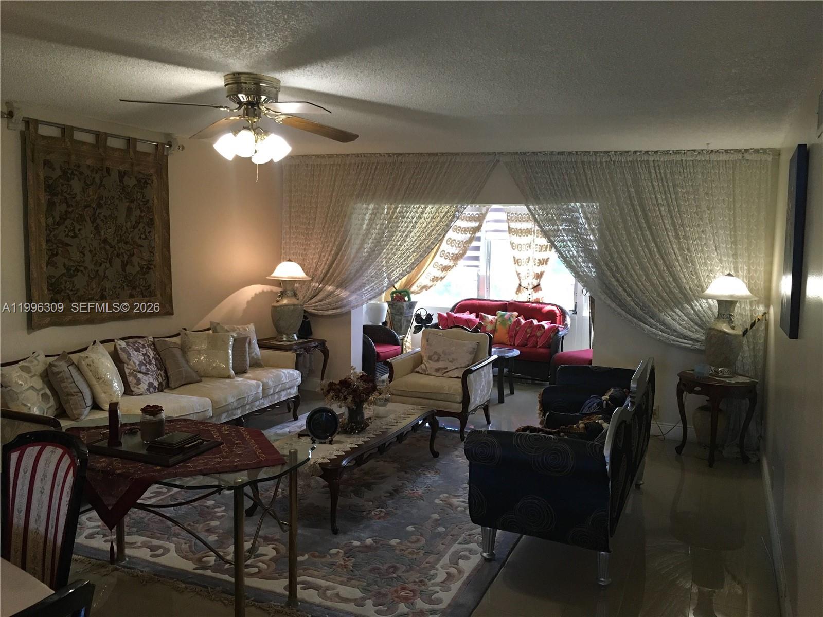 A living room features a ceiling fan, patterned area rug, and draped floor-to-ceiling windows — 300 NE 26th Ave # 314, Boynton Beach FL 33435, BOYNTON BEACH, FL