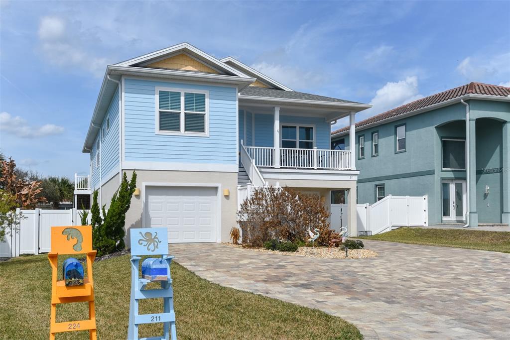 A light blue two-story house with a raised porch and a paved driveway — 211 S 26TH STREET, FLAGLER BEACH, FL