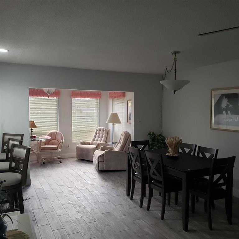 A dining area with a dark table and chairs sits adjacent to a sunlit seating space — 4105 EL DORADO COVE, BRADENTON, FL