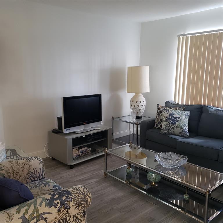 A living room features a blue sofa, a glass coffee table, and a television stand — 4105 EL DORADO COVE, BRADENTON, FL