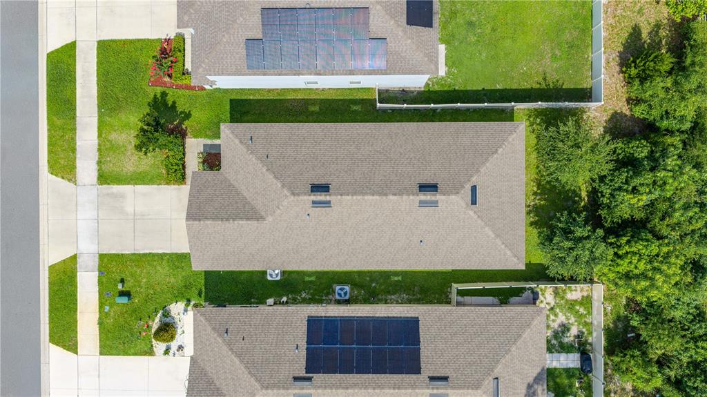An aerial view shows three suburban houses with shingled roofs, solar panels, and green lawns — 1745 BENT BRANCH AVENUE, DELAND, FL