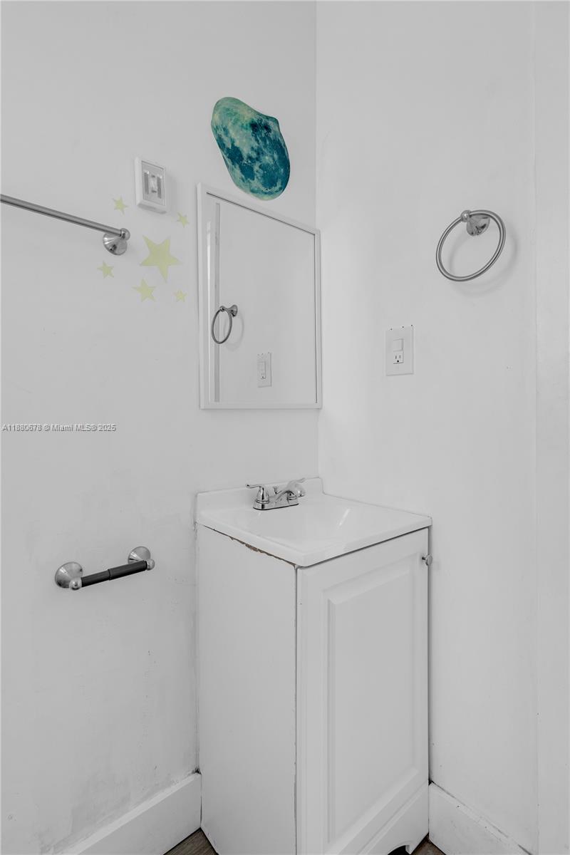 A small bathroom features a white pedestal sink, a medicine cabinet, and wall-mounted towel hardware — 110 NW 9th Ave # 3, Miami FL 33128, MIAMI, FL
