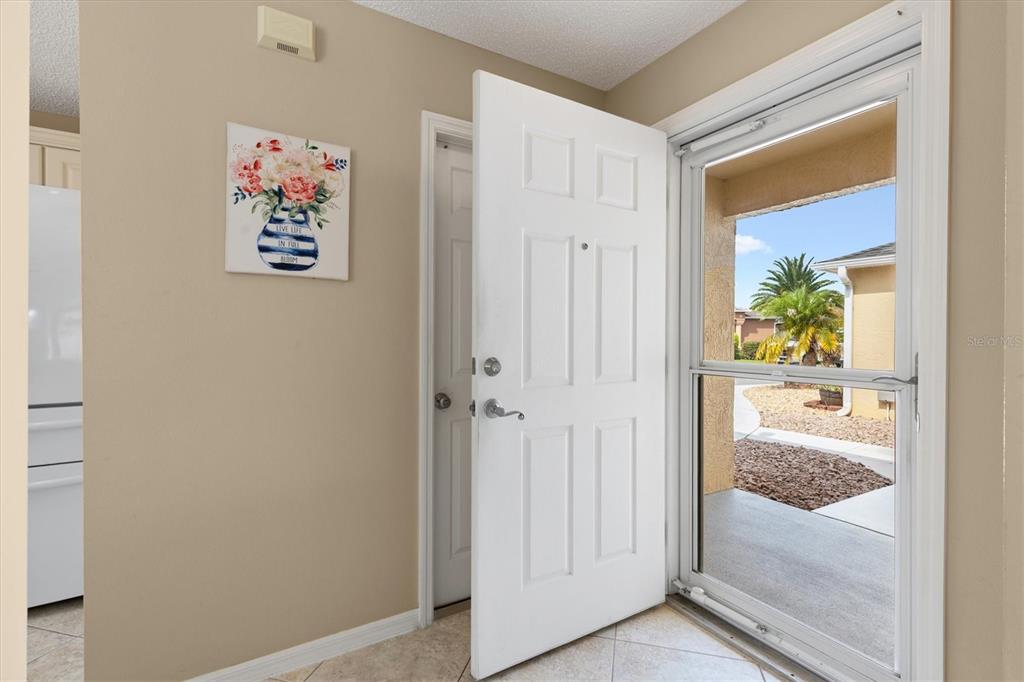 A covered entryway features a white storm door, a large window, and light-colored stucco walls — 2117 SMOAKS STREET, THE VILLAGES, FL