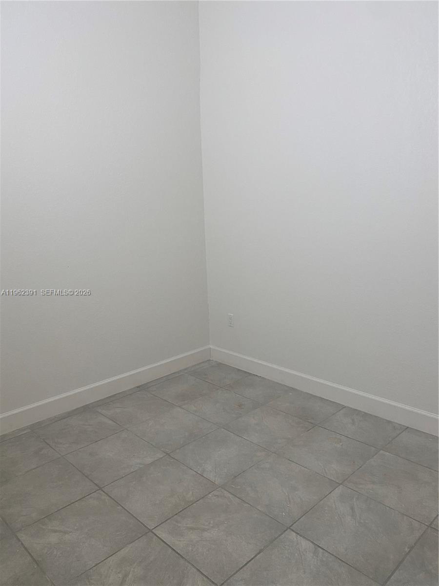 An empty room features plain white walls and light-colored square floor tiles — 10030 W Indigo St # 9, Miami FL 33157, MIAMI, FL