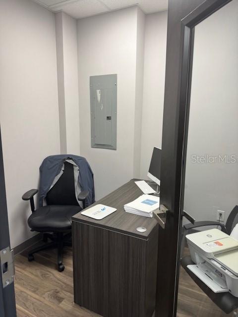 A small office features a desk, an office chair with a jacket, and a wall-mounted electrical panel — 13550 VILLAGE PARK DRIVE UNIT GE, ORLANDO, FL