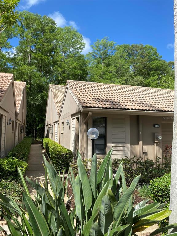 A view of a tan stucco building exterior with a tiled roof and walkway — 3134 WINDMOOR DRIVE N, PALM HARBOR, FL