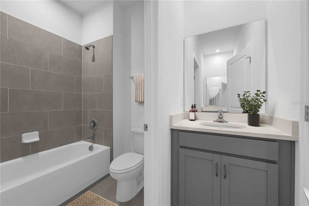 A bathroom features a gray vanity, a white tub with gray tile, and a toilet — 6629 VERBENA PLACE, LAKE HAMILTON, FL