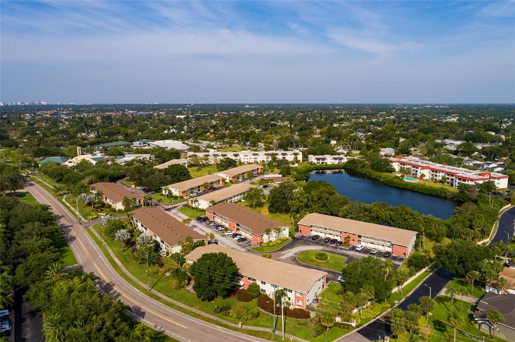 An aerial view shows several multi-story apartment buildings situated near a pond and a road — 4550 OVERLOOK DRIVE NE UNIT 154, ST PETERSBURG, FL