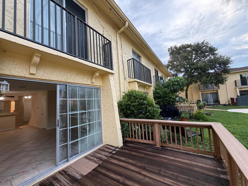A wooden deck sits outside a sliding glass door leading into a tiled interior space — 7501 GALLINETA COURT, TAMPA, FL