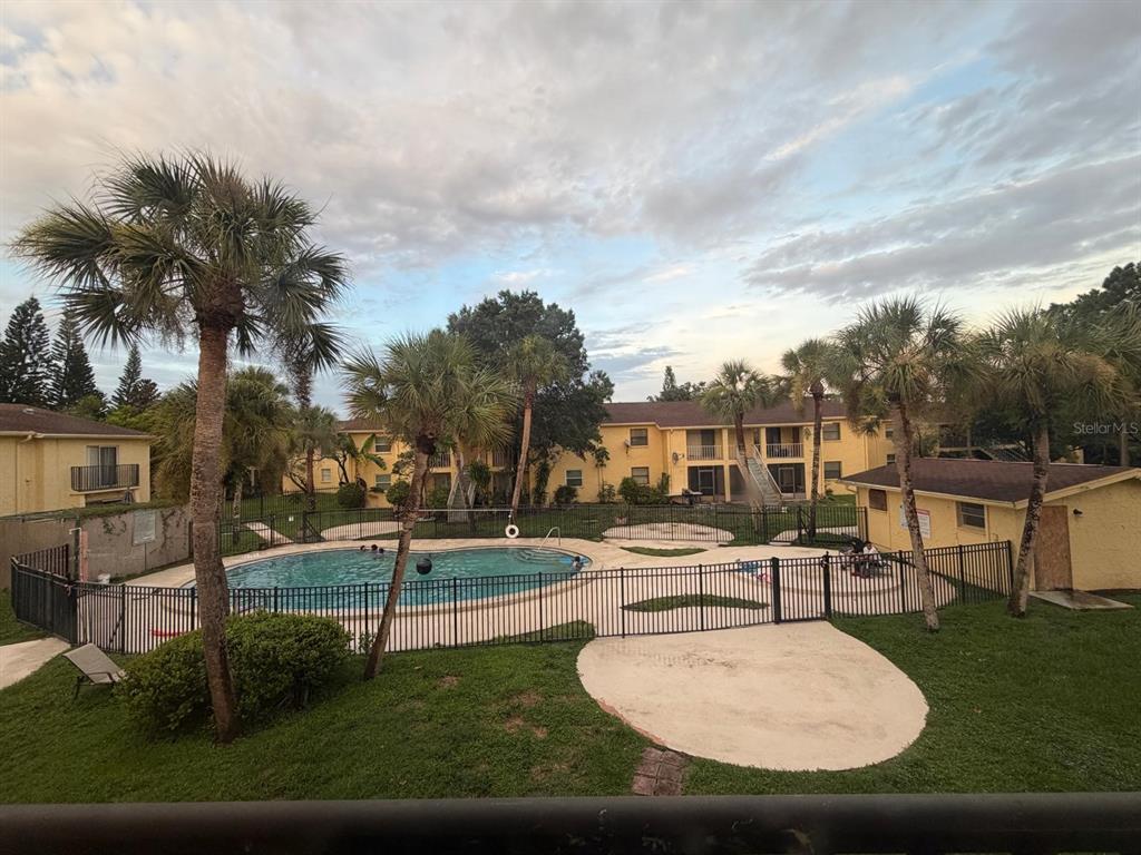 An outdoor swimming pool is enclosed by a black metal fence near apartment buildings — 7501 GALLINETA COURT, TAMPA, FL