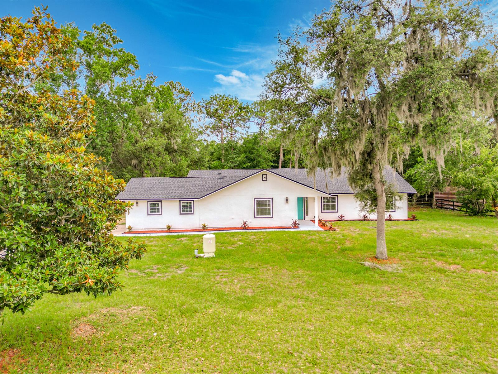 A white single-story house with a dark roof sits on a grassy lot with trees — 5534 SW 31st Street, Ocala FL 34474, OCALA, FL