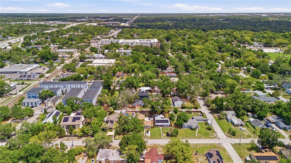 An aerial view shows a suburban neighborhood with houses, apartment complexes, and dense tree cover — 6612 N 9TH STREET, TAMPA, FL