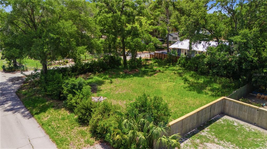 An elevated view of a vacant, grassy residential lot surrounded by trees and a fence — 6612 N 9TH STREET, TAMPA, FL