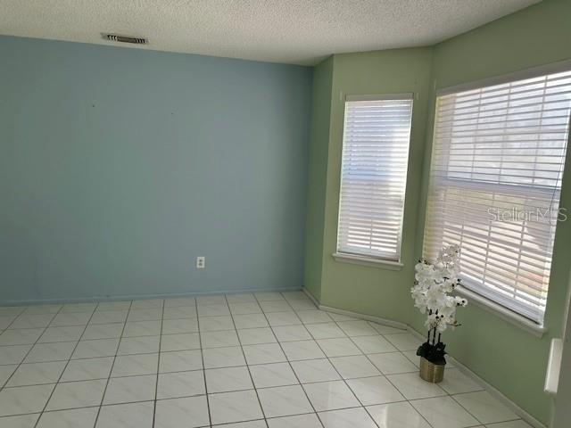 An empty room features light blue and green walls, white tile flooring, and two windows — 6926 THOUSAND OAKS ROAD, ORLANDO, FL