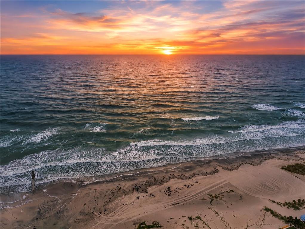 An aerial view of a sandy beach at sunset with waves rolling onto the shore — 15462 GULF BOULEVARD UNIT 903, MADEIRA BEACH, FL