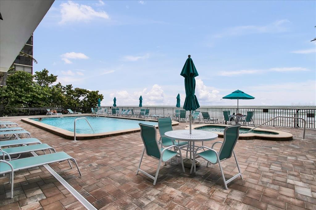 A swimming pool and hot tub are located on a paved patio overlooking the ocean — 15462 GULF BOULEVARD UNIT 903, MADEIRA BEACH, FL