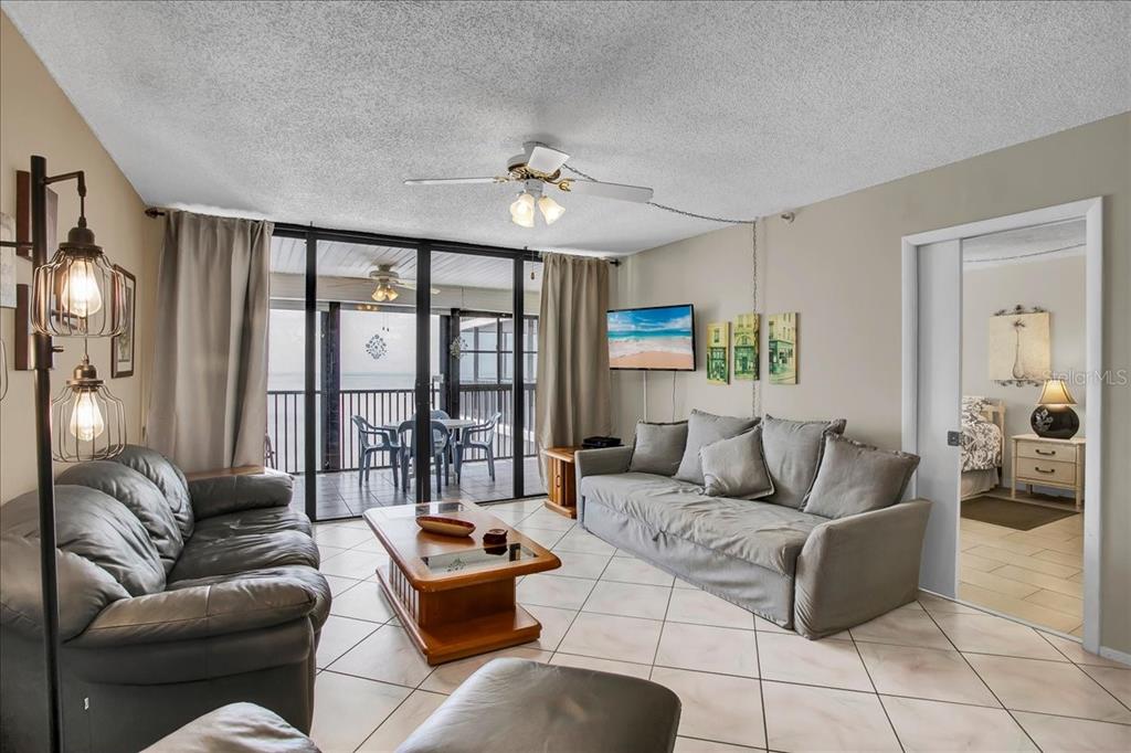 A living room features tile floors, a gray sofa, a coffee table, and a balcony view — 15462 GULF BOULEVARD UNIT 903, MADEIRA BEACH, FL