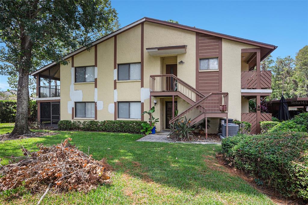 A two-story apartment building features a tan stucco exterior with brown trim and exterior stairs — 600 SUMMERHILL COURT UNIT A, SAFETY HARBOR, FL