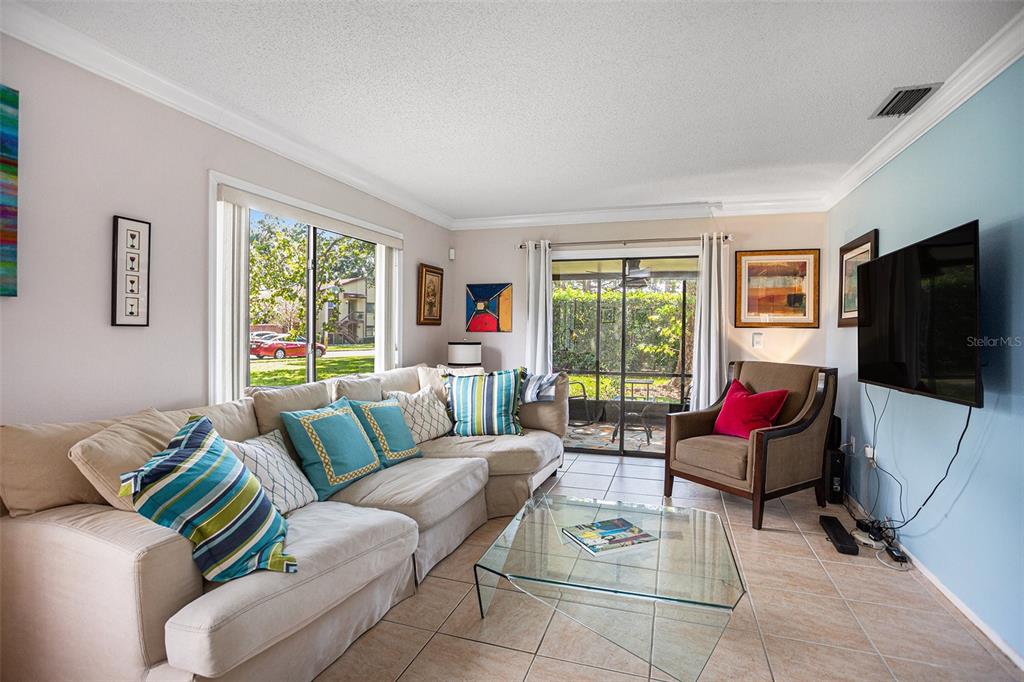 A living room features a beige sectional sofa, glass coffee table, and a wall-mounted television — 600 SUMMERHILL COURT UNIT A, SAFETY HARBOR, FL
