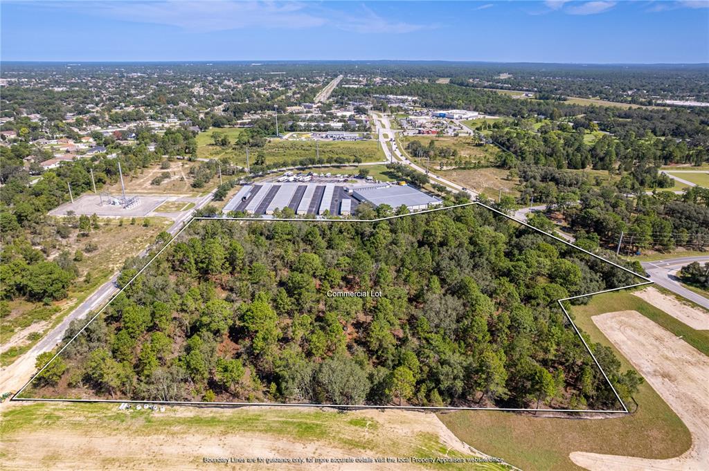 An aerial view shows a wooded commercial lot outlined in white near a parking area — 0 ANDERSON SNOW ROAD, SPRING HILL, FL