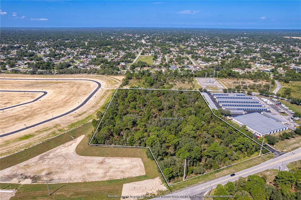An aerial view shows a wooded commercial lot bordered by a road, storage units, and construction — 0 ANDERSON SNOW ROAD, SPRING HILL, FL