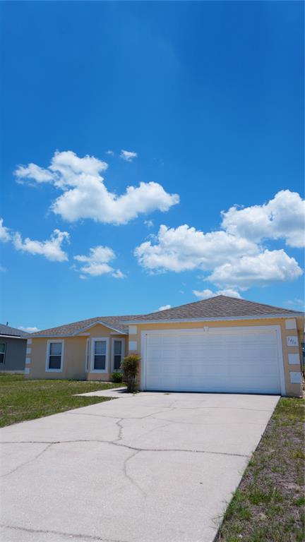 A single-story house with a yellow exterior, a two-car garage, and a cracked concrete driveway — 1417 SARASOTA DRIVE, KISSIMMEE, FL